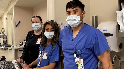 三个卫生保健工作者,戴着面具,看相机