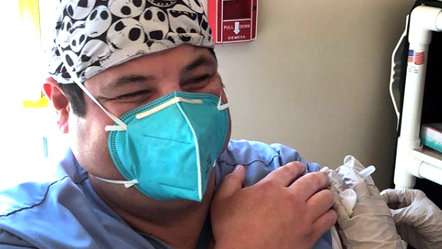年轻的拉丁裔男子，戴着蓝色口罩，正在接种疫苗
