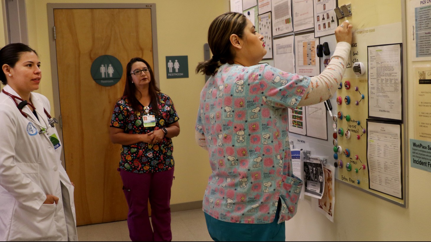 在一家诊所的走廊上，医护人员正在填写一张挤在一起的纸板