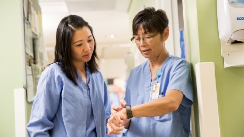 两个护士,穿着蓝色磨砂、互相交谈