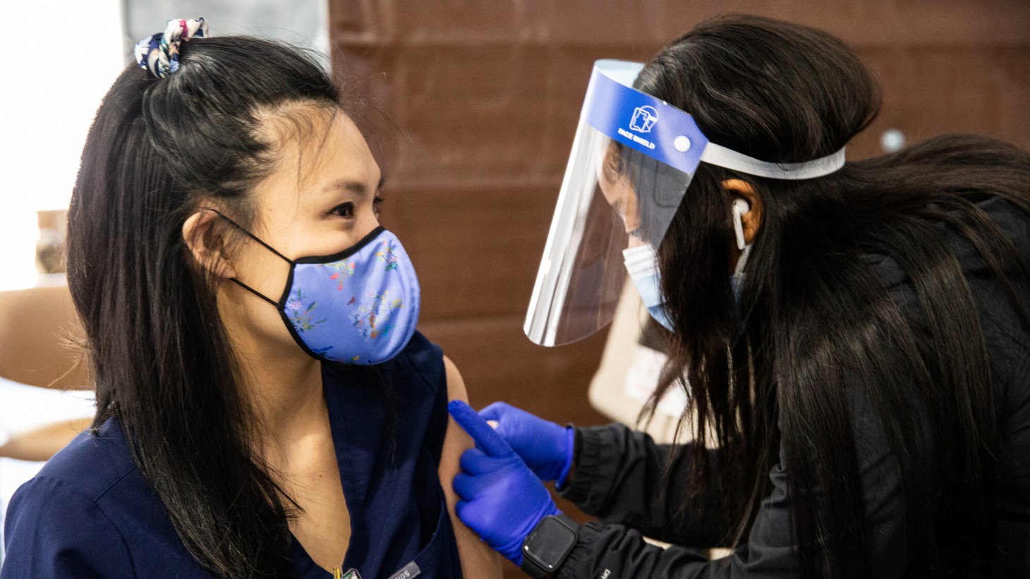 戴着面罩的医护人员正在给病人注射疫苗