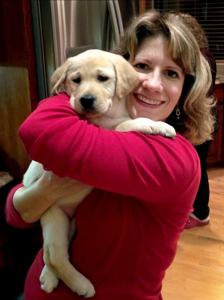 Woman wearing a red sweater holding a puppy